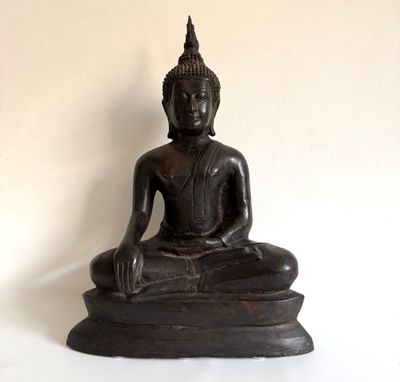 une statue de Bouddha noire posée sur une surface blanche