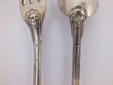 pair of silver plated spoons with ornate designs on them