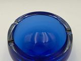 a close up of a blue glass ashtray on a white surface