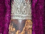 a silver and gold object in a purple velvet case