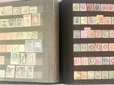 un livre ouvert, sur lequel sont posés des timbres, posé sur une table
