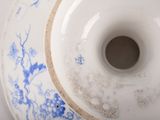 a white and blue vase with a blue flower design on it