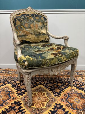an old chair with a floral upholstered seat sits on a rug