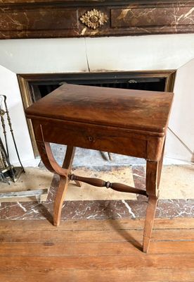 une petite table en bois munie d'un tiroir, placée devant une cheminée
