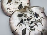 two decorative plates with birds on them on a table