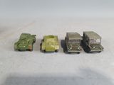 four toy army vehicles are lined up in a row on a white surface