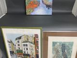 three framed paintings of a city street with buildings and a river