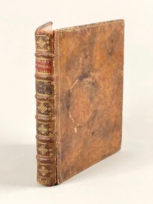 un vieux livre posé sur une table blanche à côté d'un mur blanc