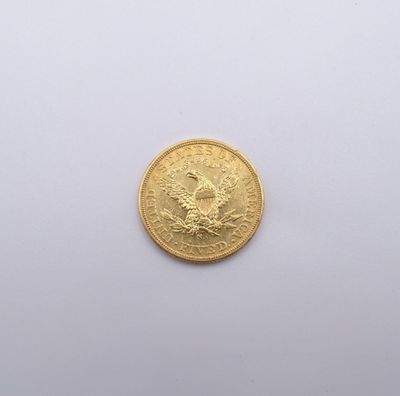 une pièce d'or ornée d'un oiseau sur une surface blanche