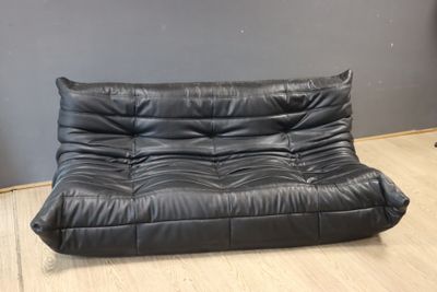 a black leather futon sofa sitting on top of a hard wood floor