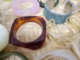 many different types of bracelets and rings on the table