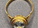 a close up of a gold ring with a blue topaz stone