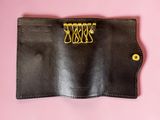 a close up of a black leather wallet with a gold clasp
