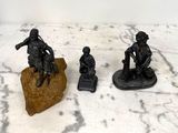 trois figurines représentant des hommes assis sur un rocher
