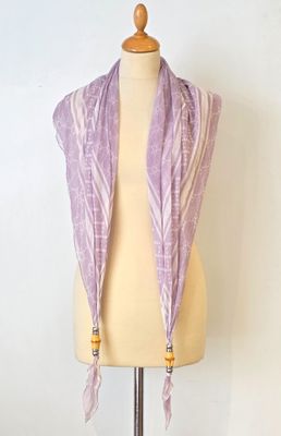 une écharpe violette posée sur un présentoir à mannequin, sur fond blanc