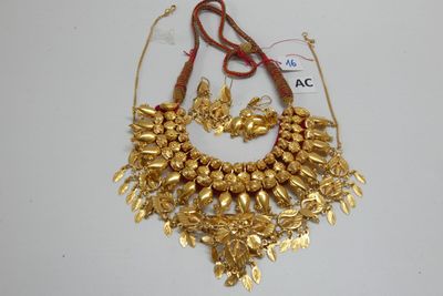Ensemble collier et boucles d'oreilles plaqués or sur un fond blanc