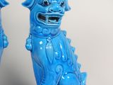 pair of blue foo foo foo statues on pedestals against a white background