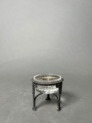 a small silver plate on a stand on a gray surface