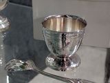 a glass table with a silver bowl and spoons on it