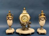 three white vases and a clock sitting on a table