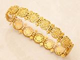 a close up of a gold bracelet on a white surface