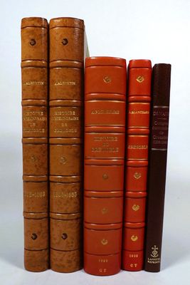 several old books are lined up in a row on a white surface