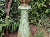 a green vase that is sitting in the middle of a garden