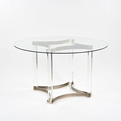 une table ronde en verre avec un piètement en métal et un plateau en verre transparent