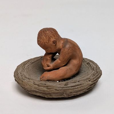 a small figurine of a boy sitting on top of a nest
