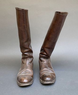 une paire de bottes en cuir marron posées sur une surface grise