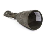 a metal bell with a tag on it on a white surface