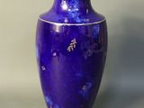 a blue vase sitting on a table against a gray wall