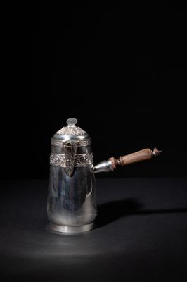 an antique silver coffee pot with a wooden handle on a black background