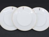 trois assiettes blanches à bord doré sur fond noir