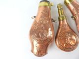 three copper colored bottles with designs on them on a white surface