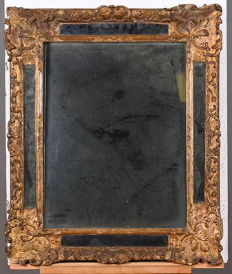 un miroir ancien dans un cadre doré, posé sur un socle en bois, avec un fond noir