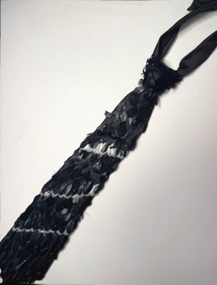 une cravate noire nouée contre un mur blanc