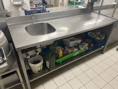 Une table évier en inox, à tablette médiane et butée