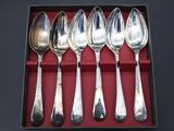 six silver spoons in a red box on a black surface