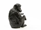 black sculpture of a monkey sitting on a white surface
