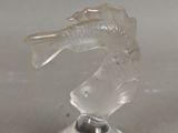un poisson en verre transparent posé sur un socle, sur une table