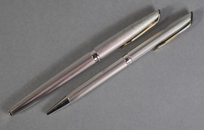 two silver pens sitting next to each other on top of a table