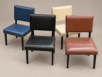 quatre fauteuils en cuir de couleurs différentes, disposés les uns à côté des autres sur une surface grise