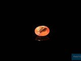 un gros plan d'une petite pierre orange posée sur une surface noire