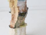 a small vase that has a piece of wood on top of it