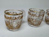 three glass cups with gold designs on them sitting on a white surface