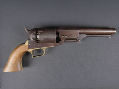 un gros plan d'un revolver posé sur une table, sur fond noir