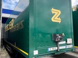 two green semi trucks parked in a parking lot