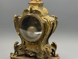une image représentant une horloge de couleur dorée posée sur un socle en bois