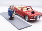 a figurine of a man standing next to a red car